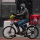 A Grubhub delivery driver carries food on a bike through the snow